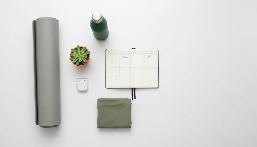 Flat-lay s podložkou na jógu, láhví na vodu, aktivním oblečením a diářem pro udržení pohybového minima